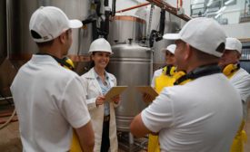 meeting in a brewery between collared professional and frontline safety workers