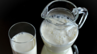 glass pitcher and cup of milk black background