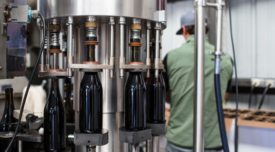 glass wine bottles being filled by machine at factory