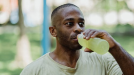 man drinking lime green drink from bottle