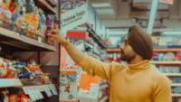 man in grocery store looking at chip bag label