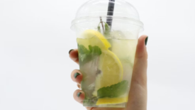 person's hand holding plastic cup of lemonade